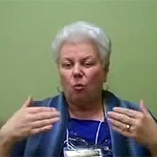 An older woman gestures as she describes being healed through prayer