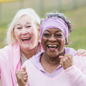 Two older woman laugh and raising their fists triumphantly