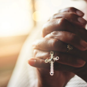 Praying hands clasp a rosary