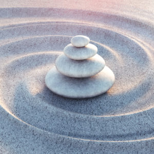 a stone sculpture evokes carefully balanced pebbles sitting at the center of whirled sand