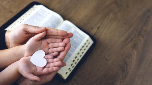 Heart in hands on a bible
