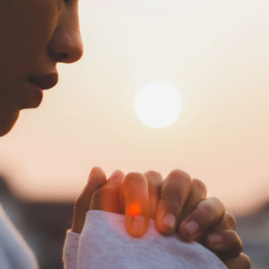Profile of a woman holding her hands up in prayer