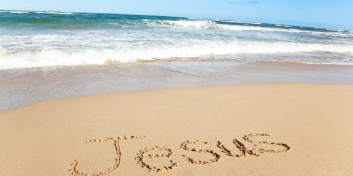 'Jesus' is written in the sand on the seashore