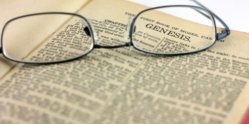 A pair of reading glasses rest on an open bible