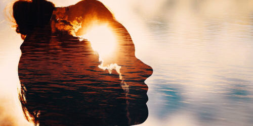 Multiple exposure image; glaring sun from behind a cloud, a woman's silhouette looking toward the sky, a backdrop of rippling water