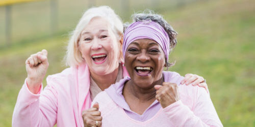 Two older woman laugh and raising their fists triumphantly