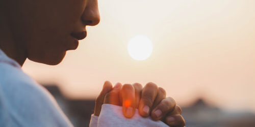 Profile of a woman holding her hands up in prayer